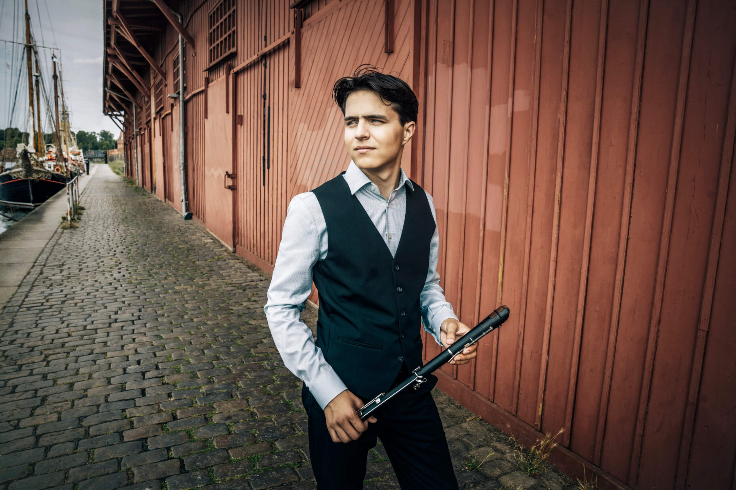 Der Flötist Andreas Kammenos mit seinem Instrument auf einer Straße.